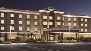 Un grand hôtel à plusieurs étages, reconnaissable à son enseigne bien visible indiquant « Country Inn & Suites ». Il se distingue par sa façade en briques, dotée de nombreuses fenêtres et d’une entrée abritée.