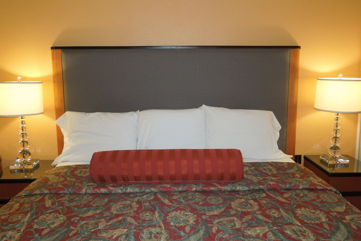 A hotel room with a bed, two bedside lamps, and a patterned bedspread.