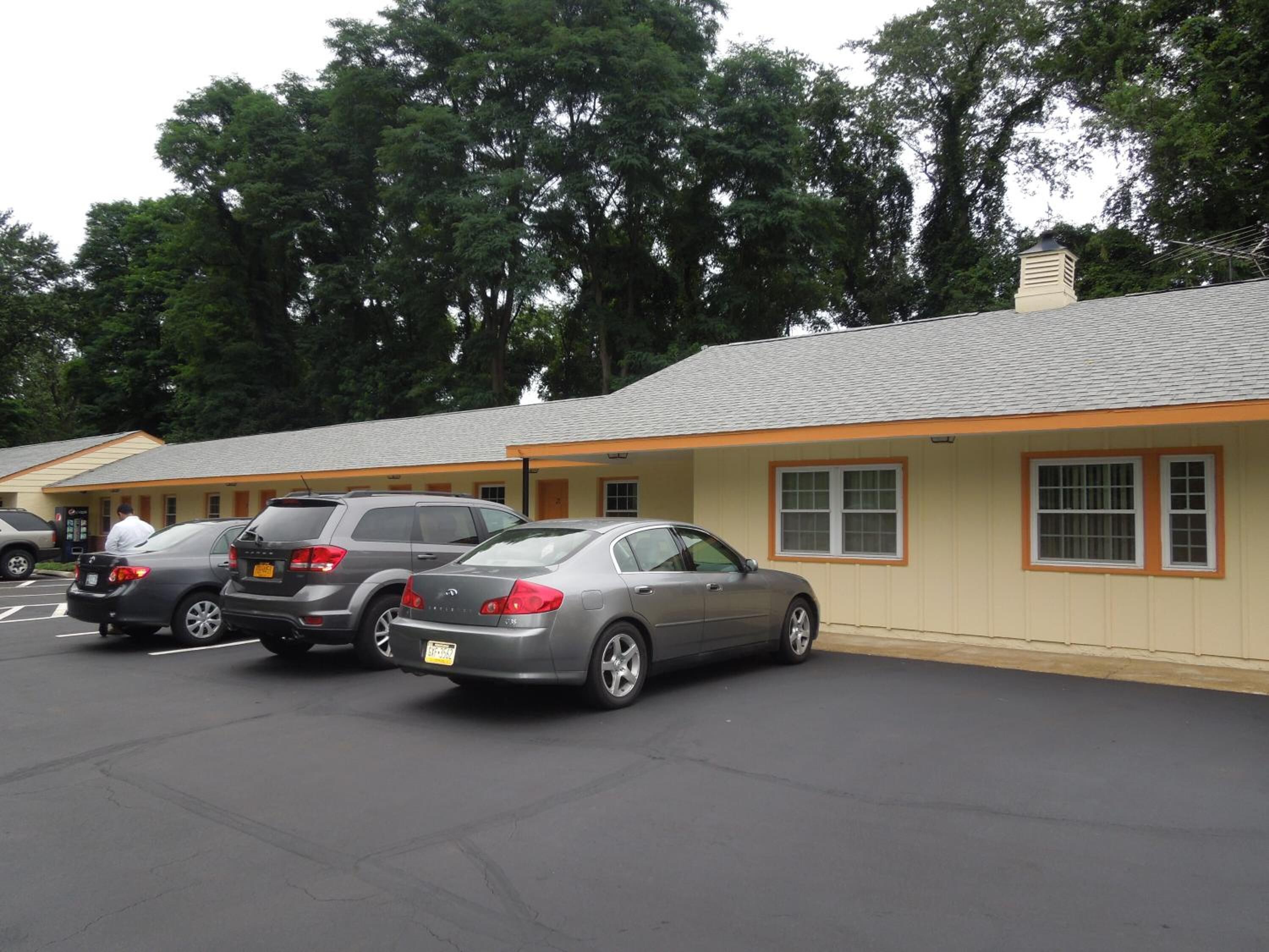 A parking lot with several cars parked in front of a building with a sloped roof and a beige facade.