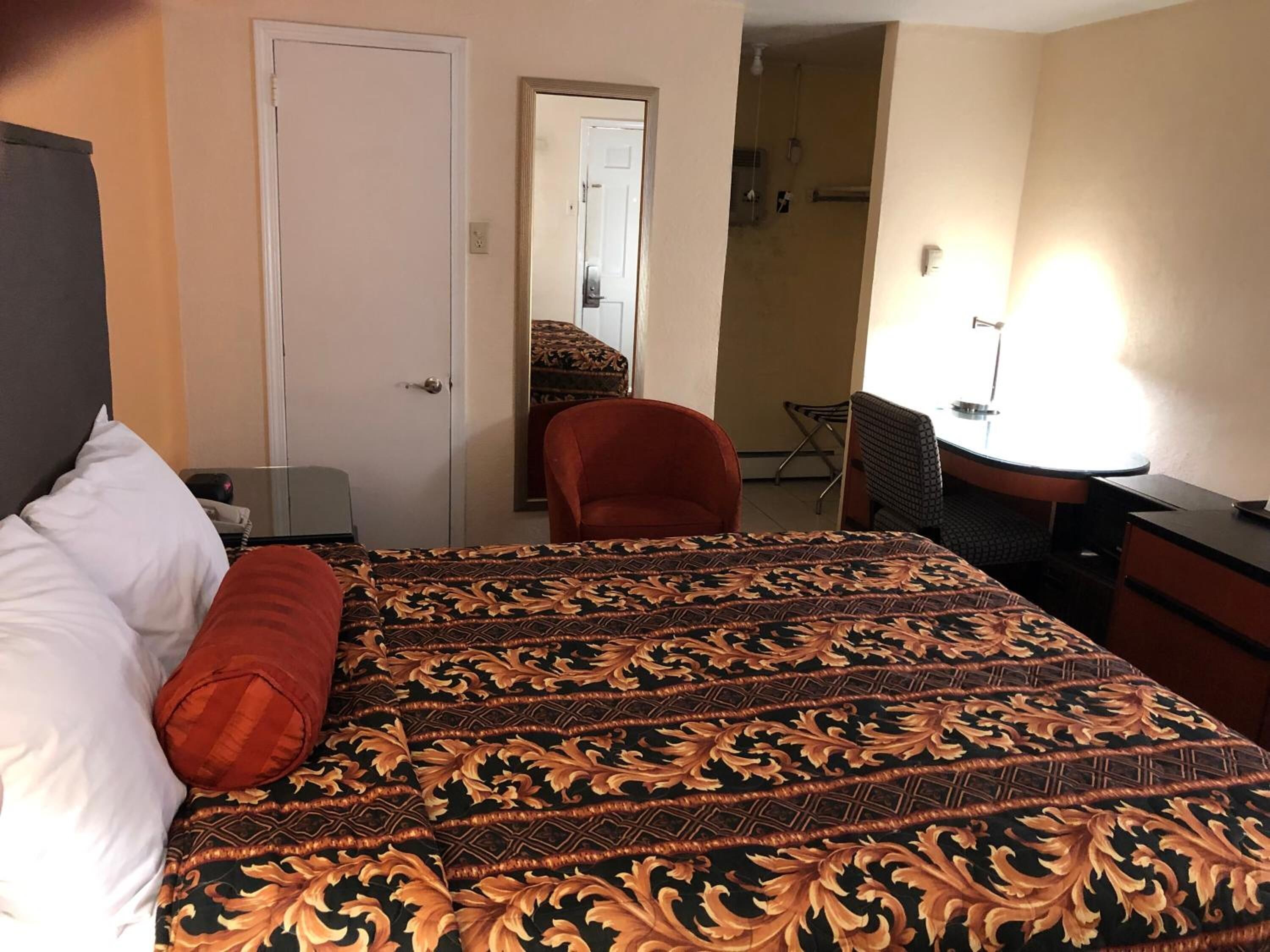 Habitación de hotel con cama, escritorio, una silla y baño a la vista tras una puerta abierta.