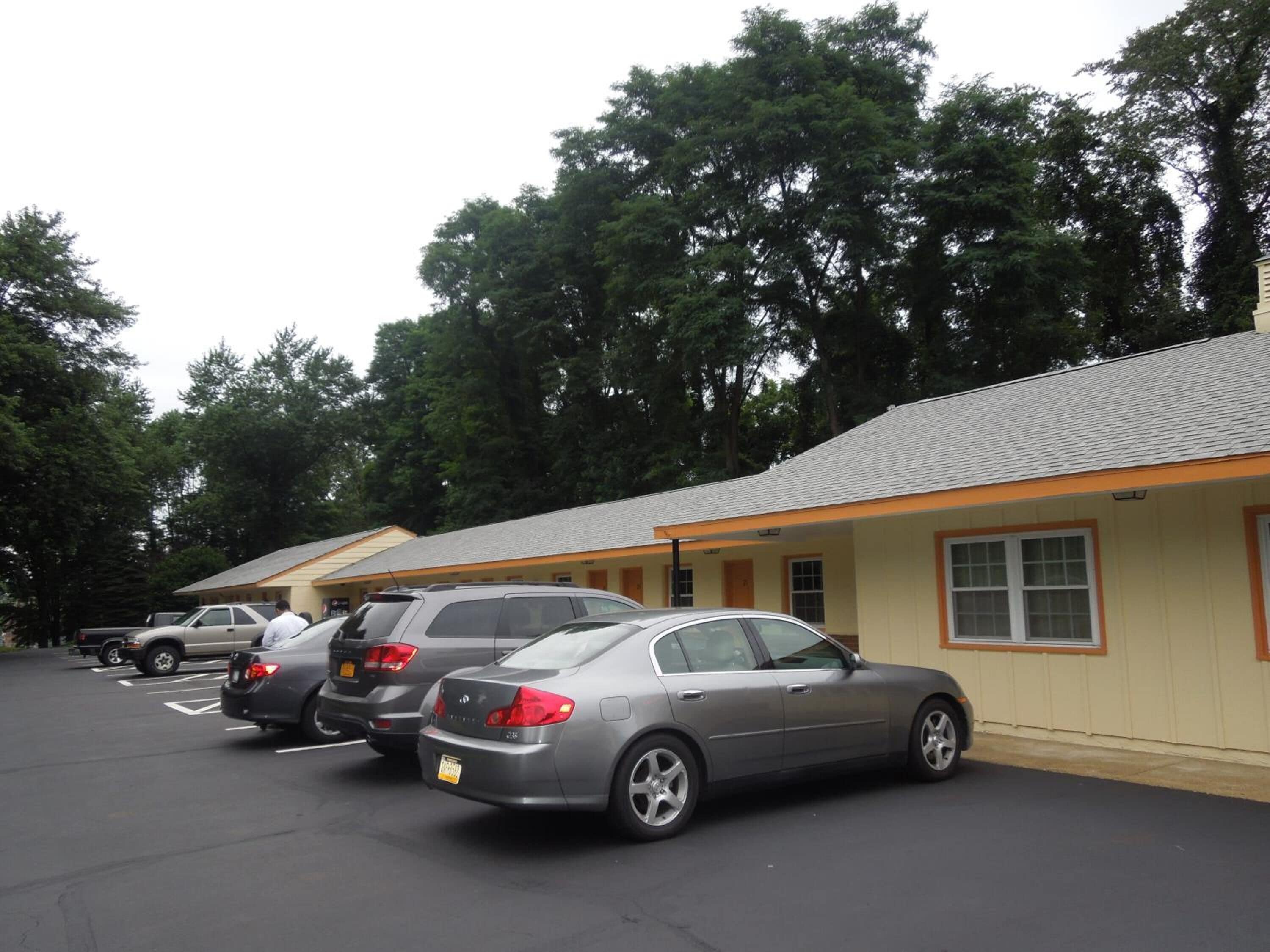 Uma fileira de quartos de motel com um estacionamento na frente.