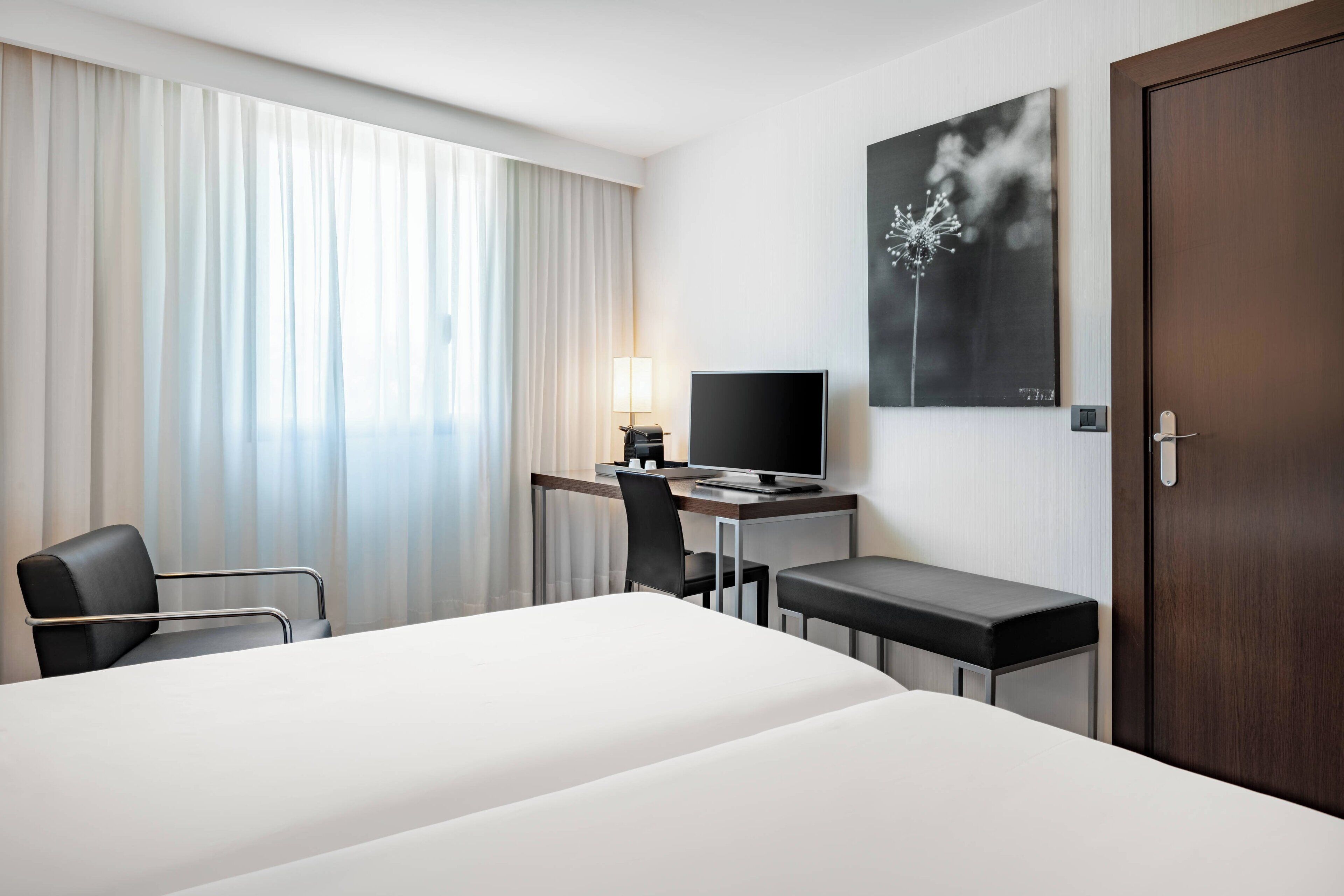 Ein Hotelzimmer mit Bett, Schreibtisch mit Computer, Stuhl und Fernseher.