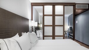 Quarto de hotel com uma cama grande, uma escrivaninha e um guarda-roupa.