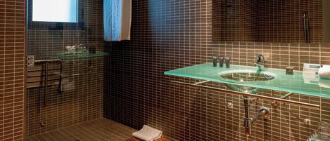 A modern bathroom with a glass shower enclosure, a glass sink, and a large mirror.