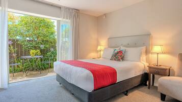 A hotel room with a bed, two bedside lamps, a small table, and a chair.