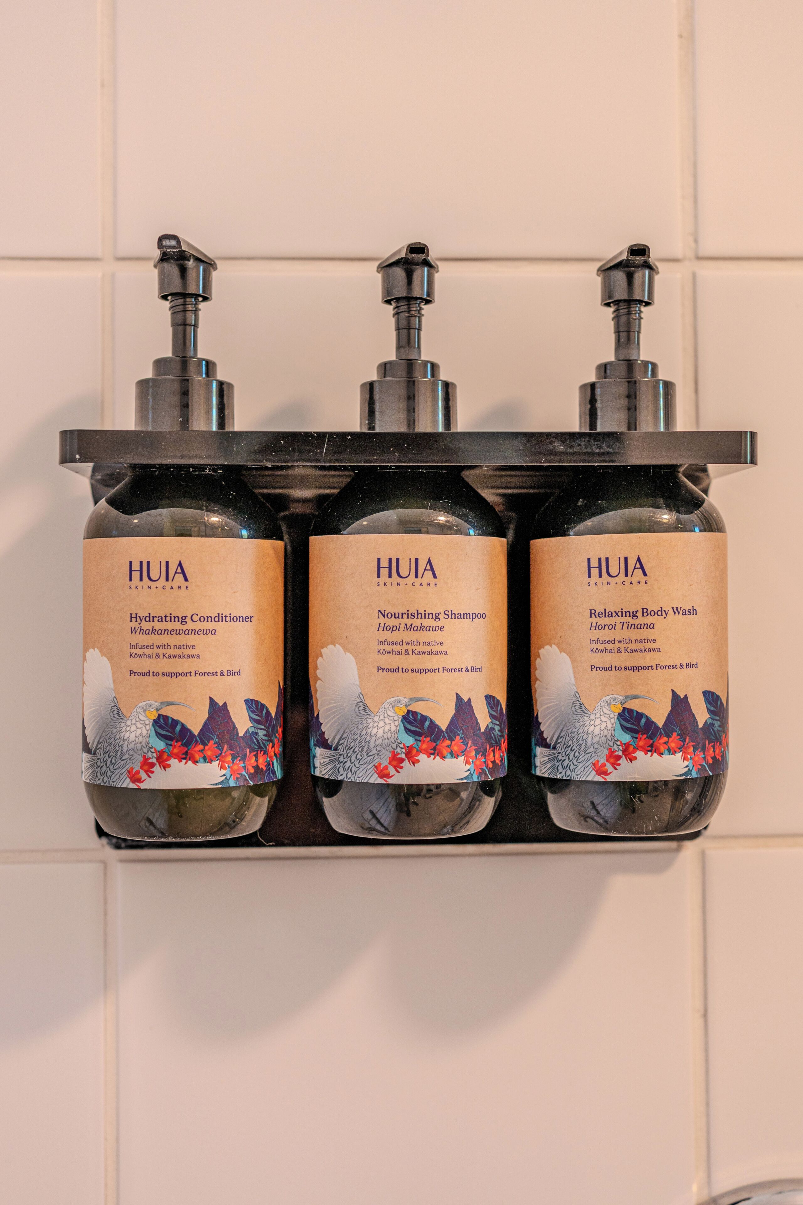 Tres productos de cuidado facial HUIA en un dispensador montado en la pared.
