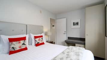 Una habitación de hotel con cama, mesita de noche, escritorio y baño.