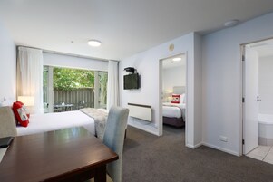 Habitación de hotel con cama, escritorio, silla, televisor montado en la pared y vistas al exterior.
