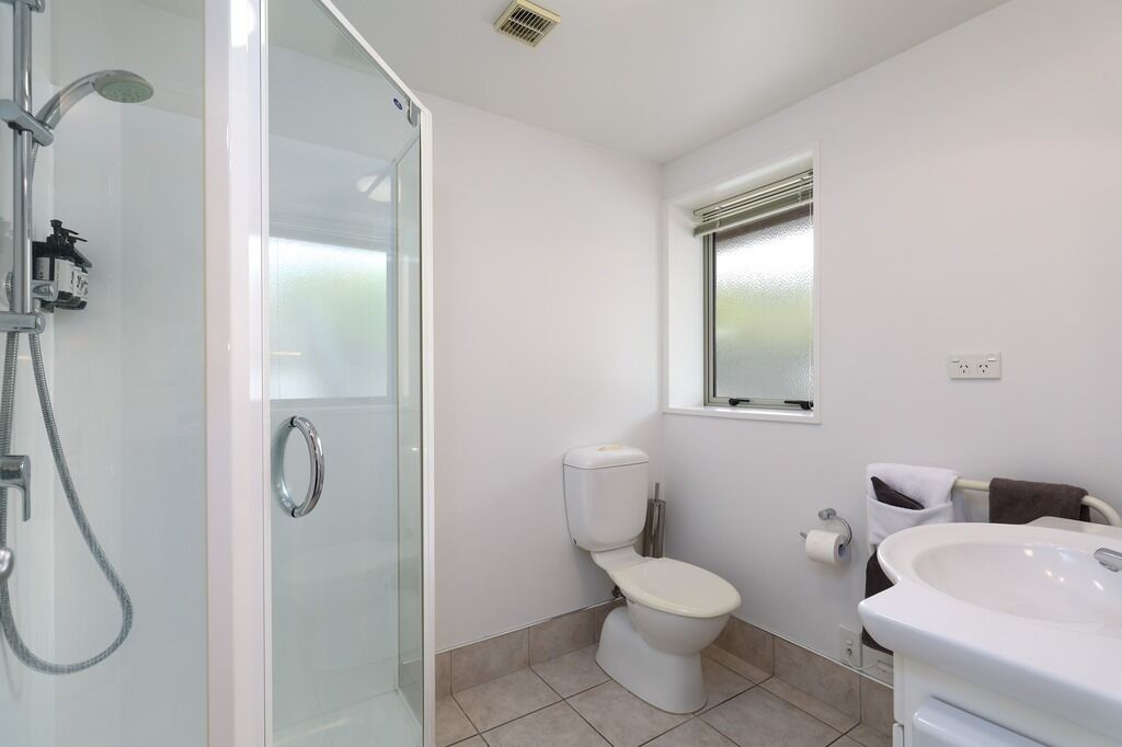 Un baño moderno con ducha de vidrio, inodoro, lavamanos y ventana.