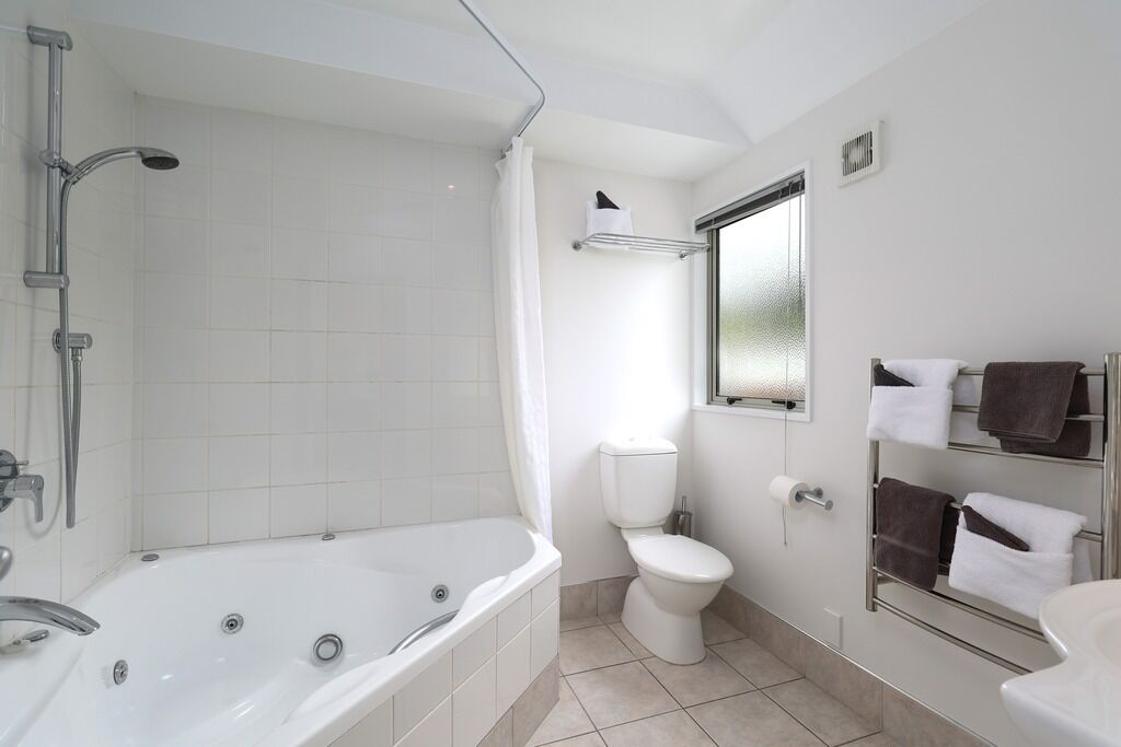 A modern bathroom with a bathtub, toilet, and a glass-enclosed shower.