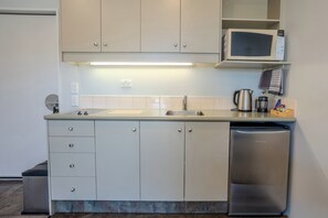 A compact kitchen with a microwave, sink, and dishwasher. - Chelsea Park Motor Lodge Nelson (Nelson)