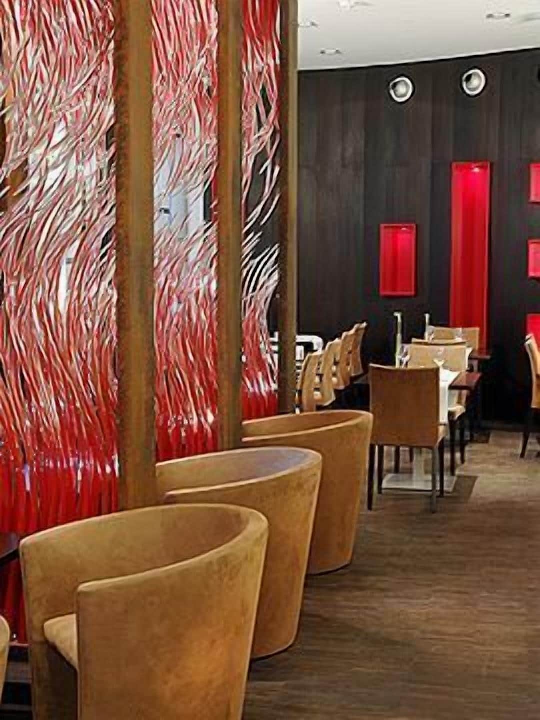 A restaurant with a modern interior, featuring wooden chairs and tables, and red decorative panels.