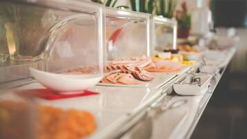 Ein Buffet mit verschiedenen Speisen, darunter geschnittenes Fleisch und Gemüse, präsentiert auf einer Marmorplatte.
