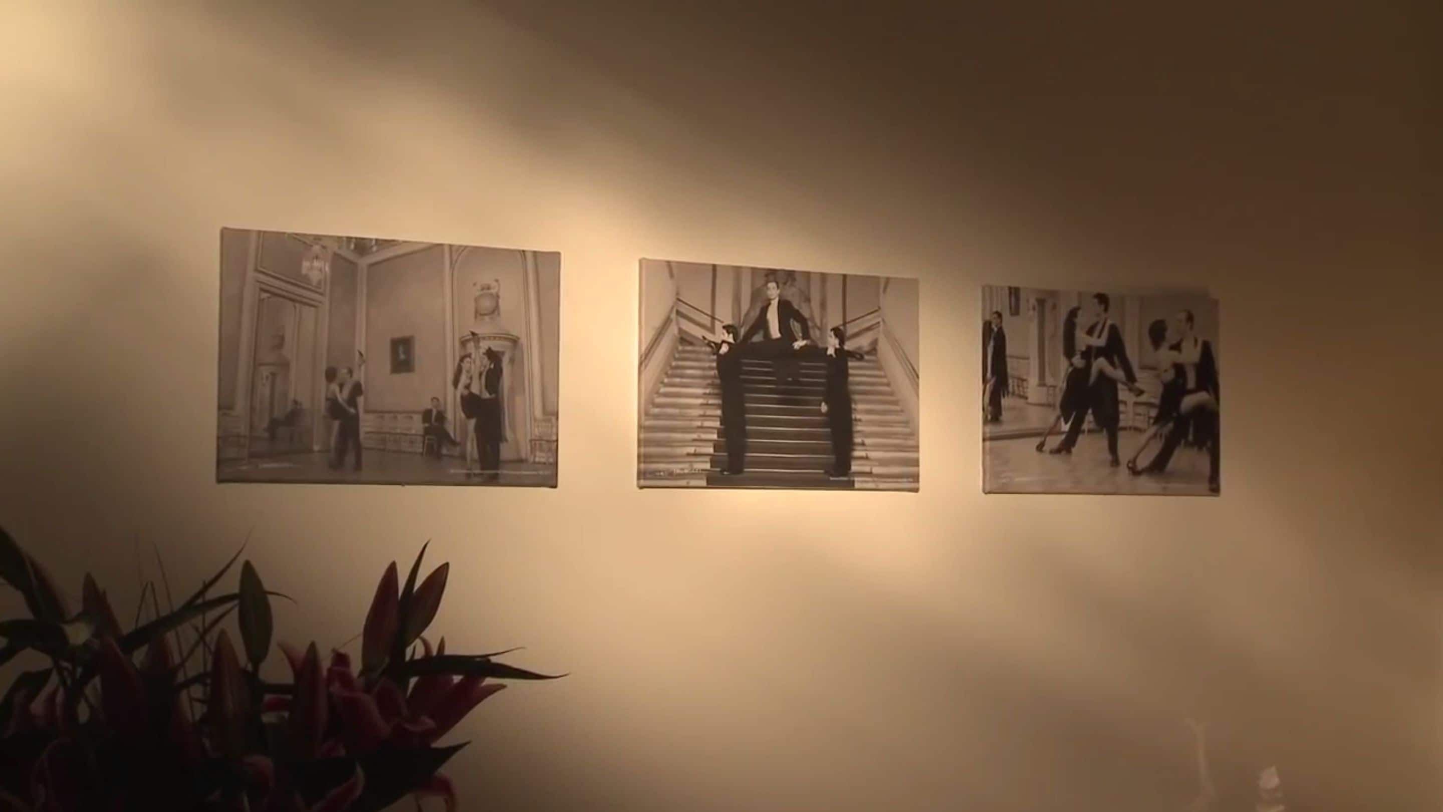 Three black and white photographs on a wall, depicting various indoor scenes.