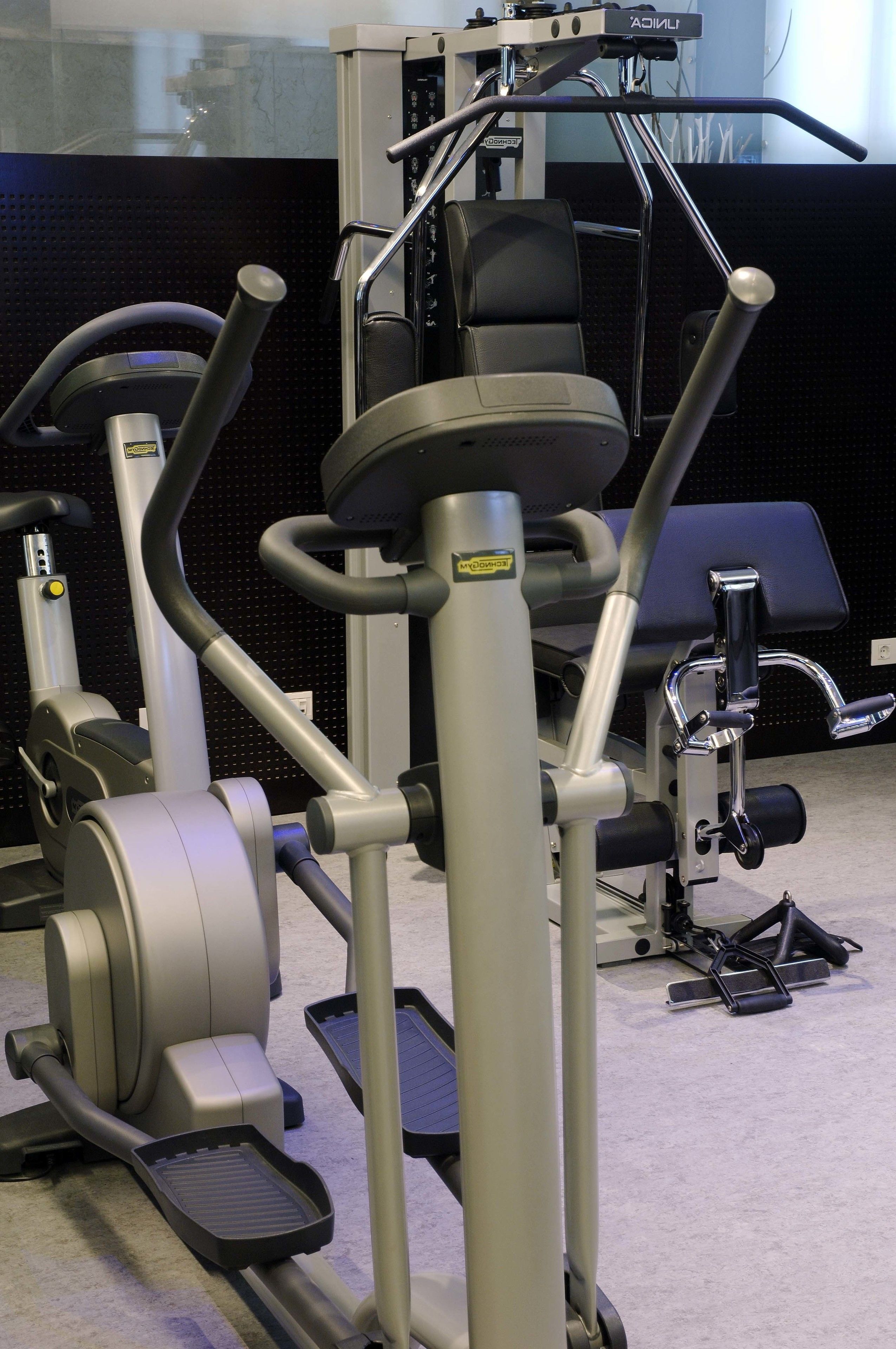A gym with various exercise equipment including treadmills, elliptical machines, and weight machines.