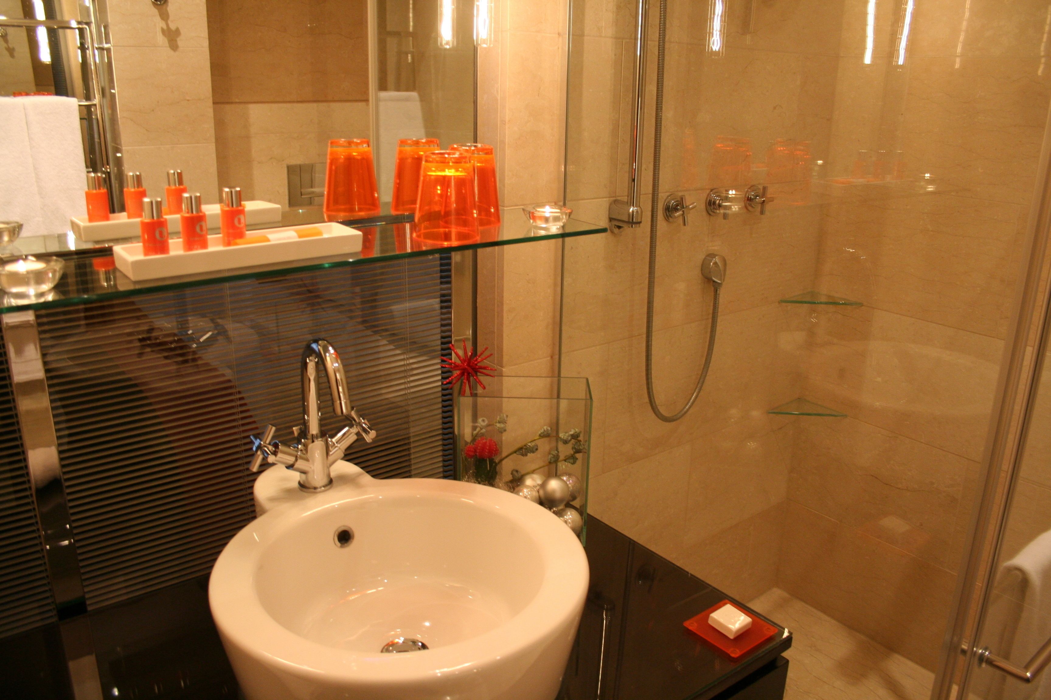 A modern bathroom with a glass sink, a shower, and a mirror.