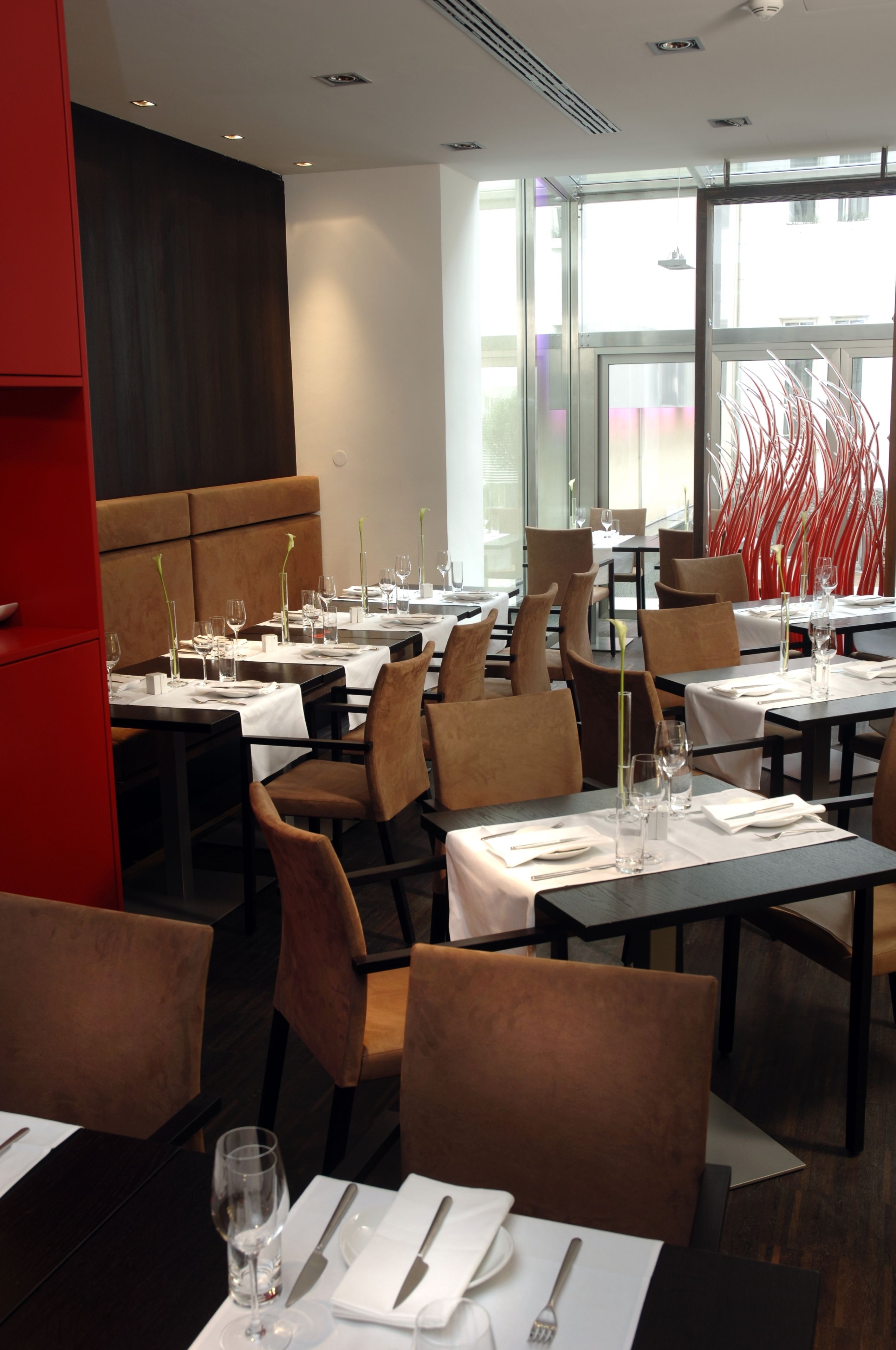 Um restaurante moderno com mesas preparadas para refeições, com uma combinação de assentos em cabines e cadeiras.