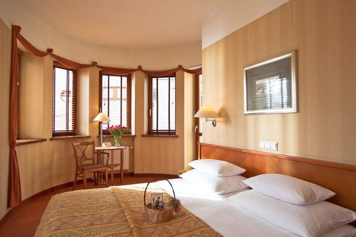 Una habitación de hotel con una cama grande, un escritorio con una silla y una ventana con cortinas.