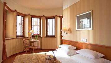 Habitació d'hotel amb un llit gran, una taula de treball amb una cadira i una finestra amb cortines.