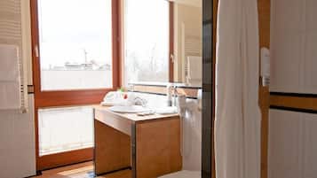 Un baño moderno con un amplio ventanal, un lavabo, un inodoro y una zona de ducha.