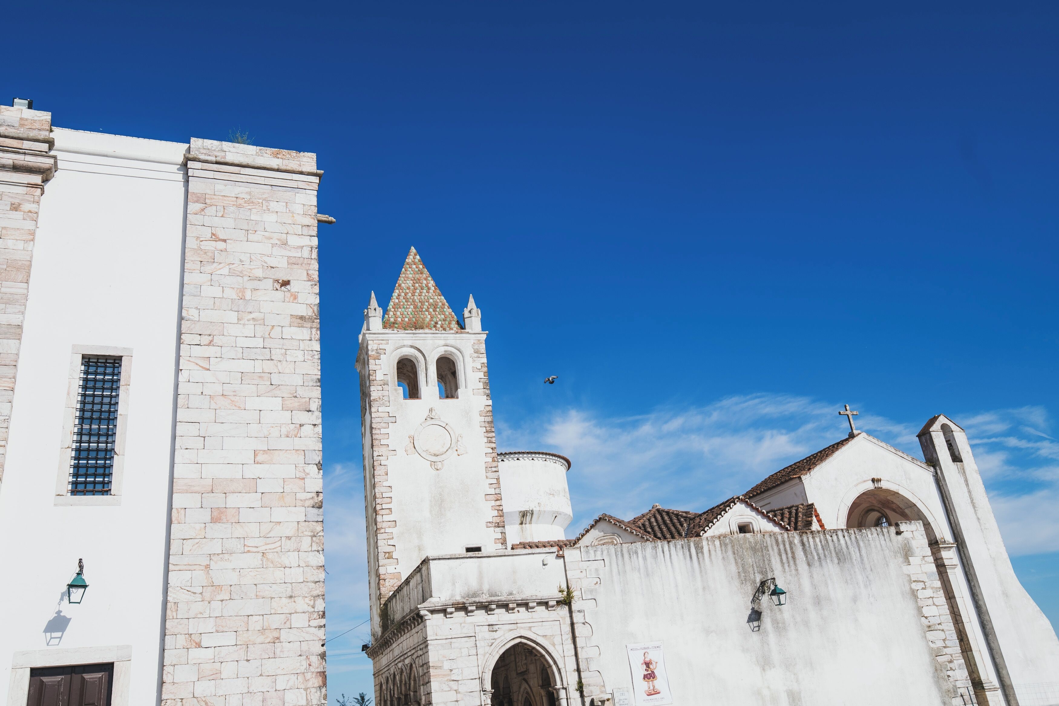 Una iglesia histórica con un campanario, ventanas de arco y una cruz en la parte superior.