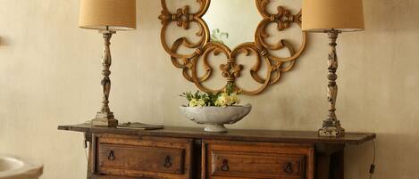 Un aparador de madera con dos lámparas, un espejo y un florero con flores.