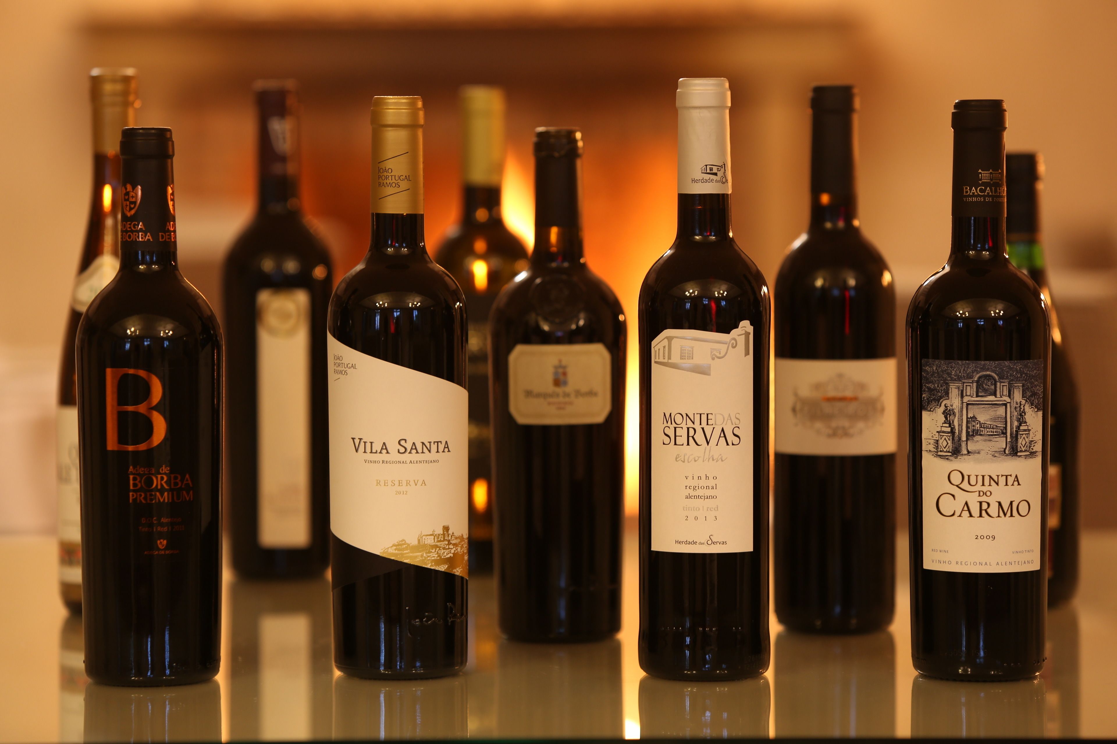 Várias garrafas de vinho sobre uma superfície refletora.