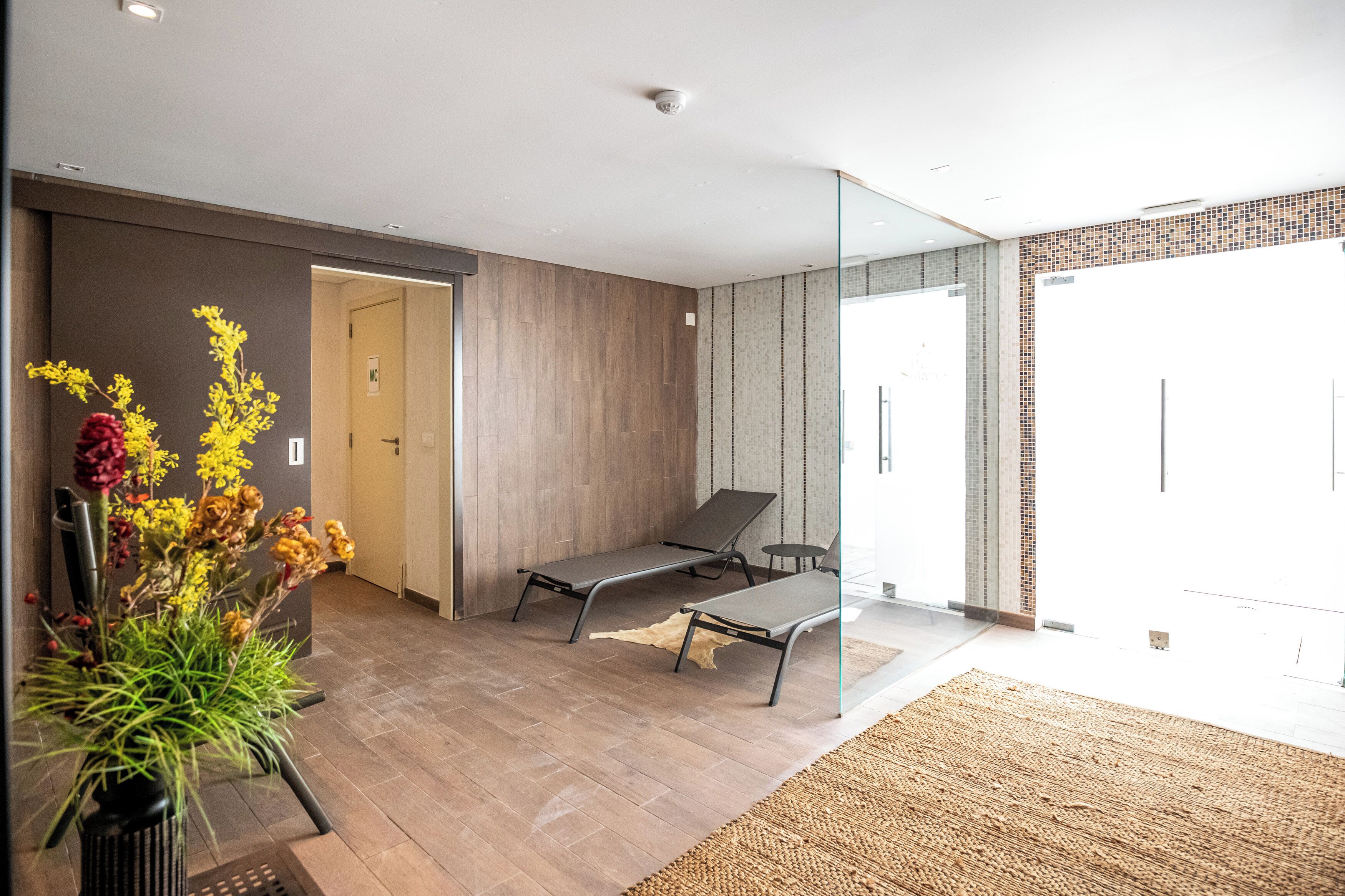 Un intérieur moderne avec un plancher en bois, une porte vitrée donnant sur l’extérieur et un banc.