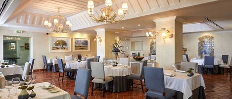 A restaurant with multiple tables, chairs, and a chandelier.