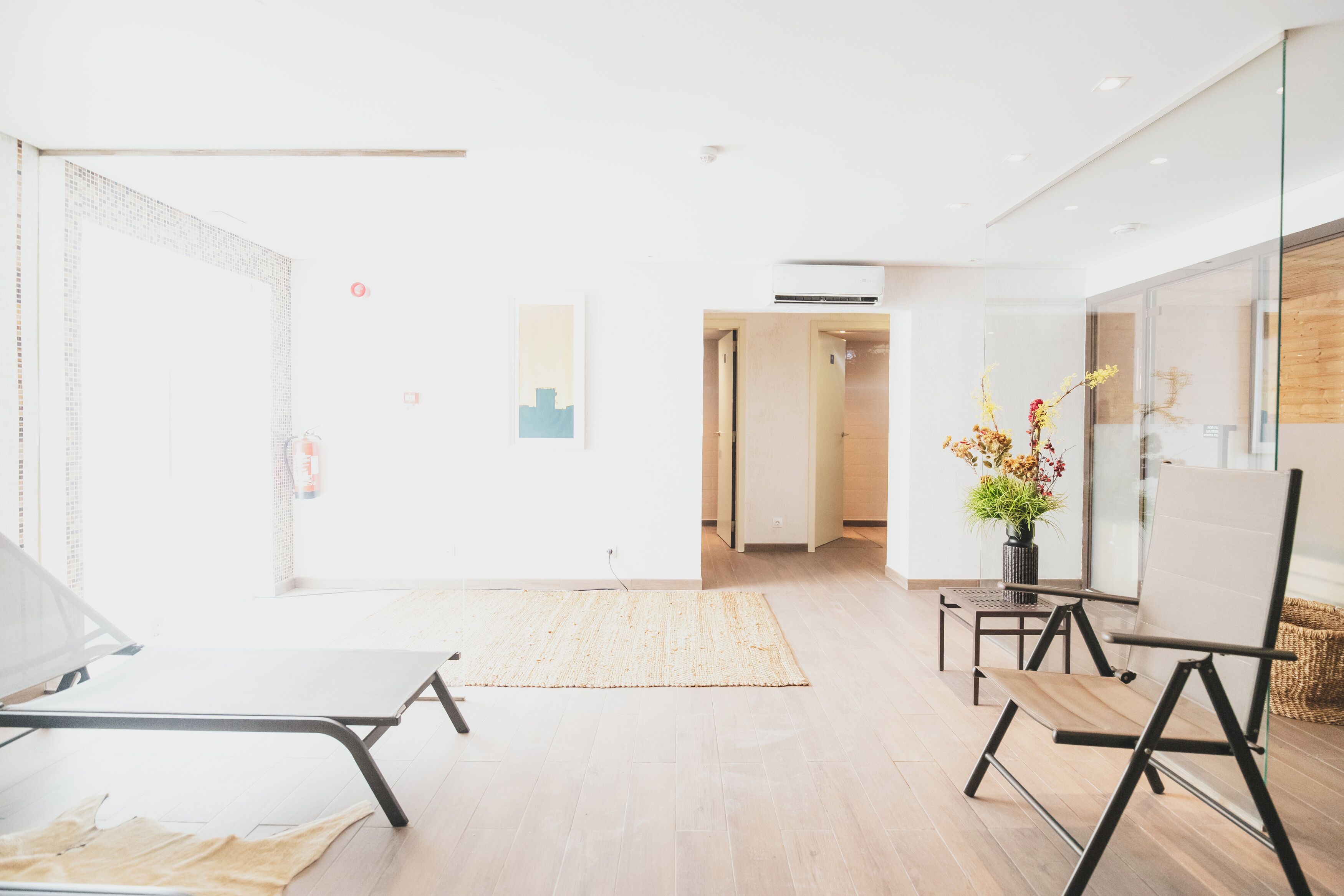 A bright, modern room with a large window, a whiteboard, and a small table with a vase of flowers.