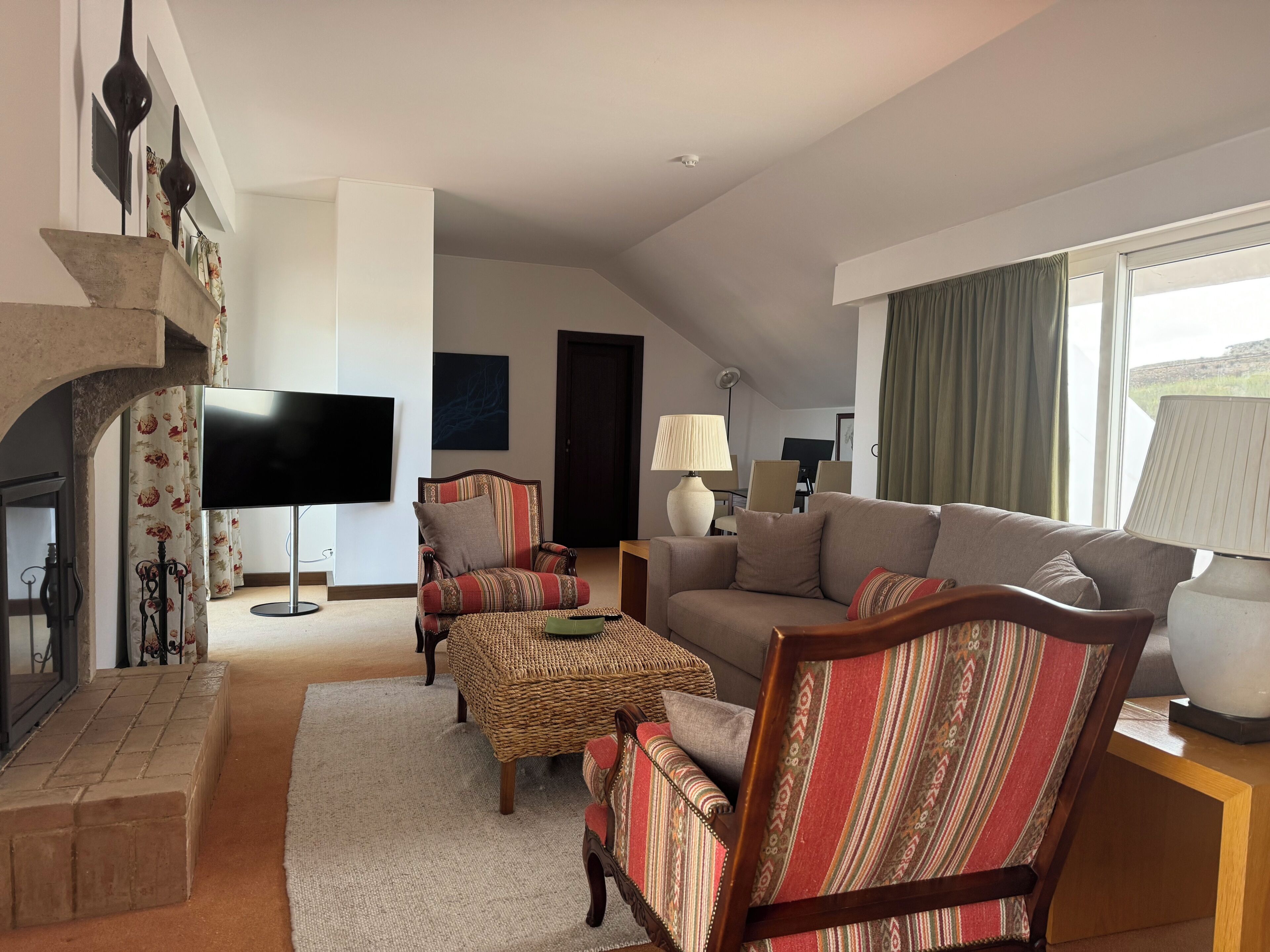 A living room with a sofa, armchairs, a television, a fireplace, and a view of the outdoors.