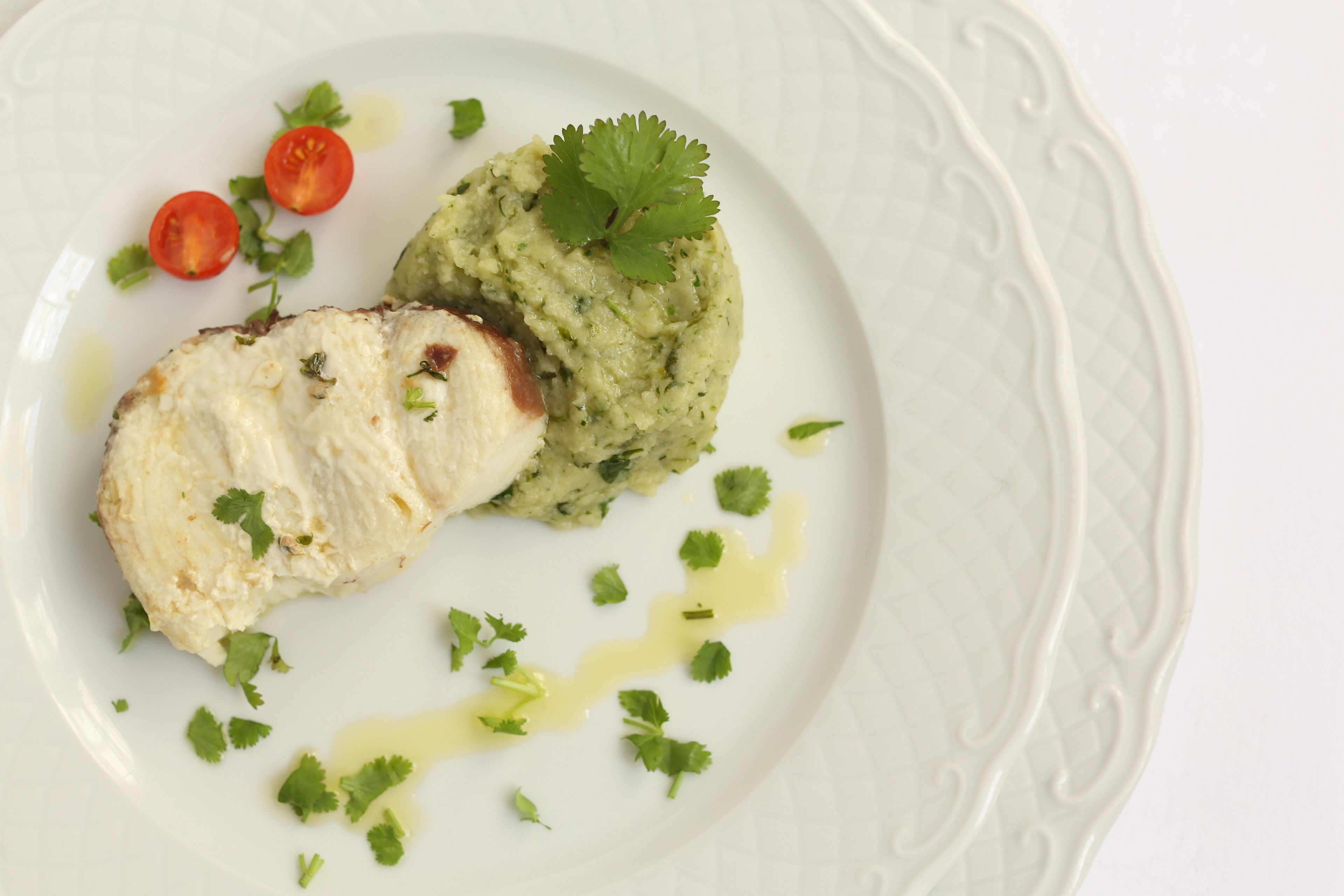 Une assiette contenant un morceau de poisson, de la purée de pommes de terre et des accompagnements.