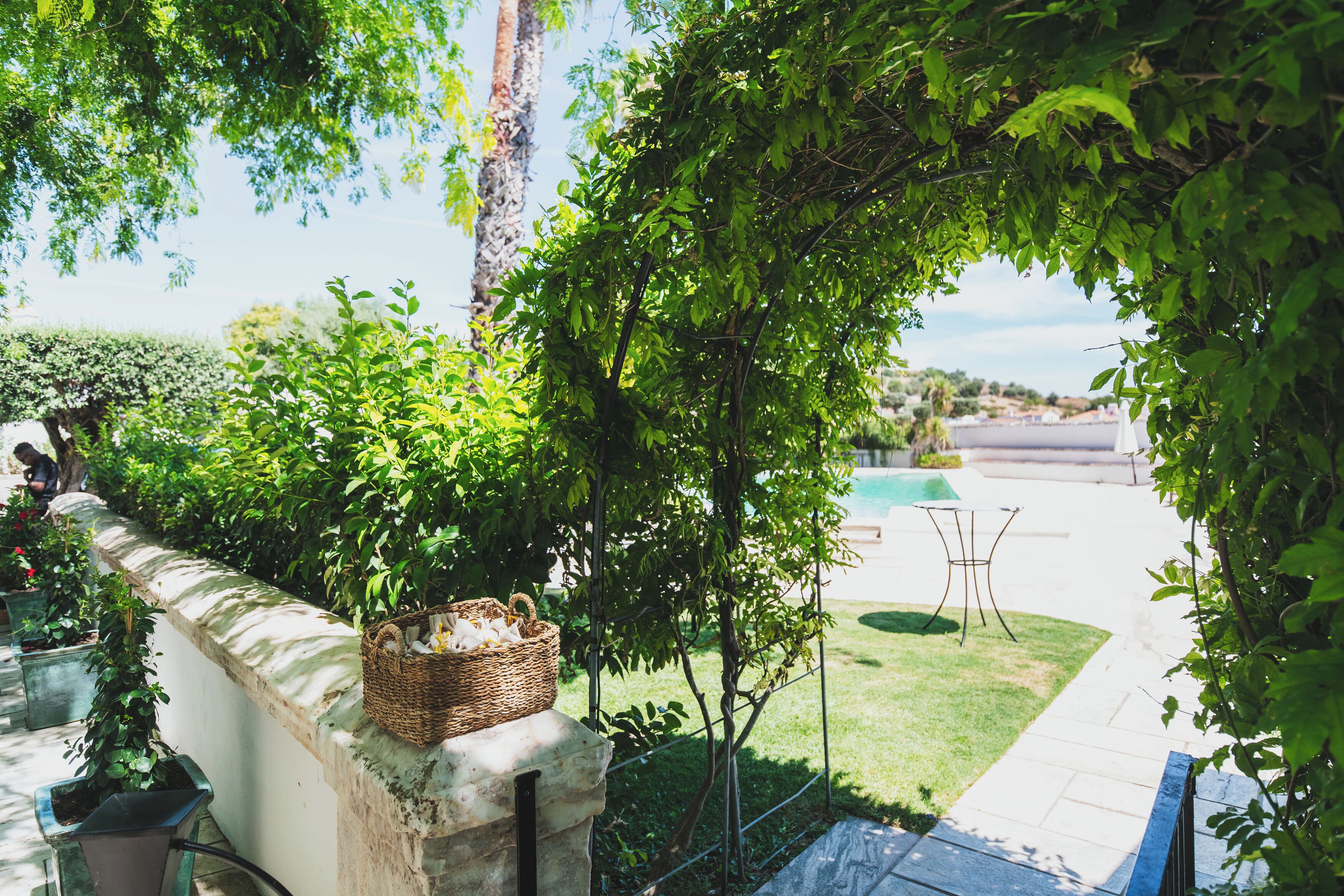 A garden area with a stone wall, a wicker basket, and a metal table.