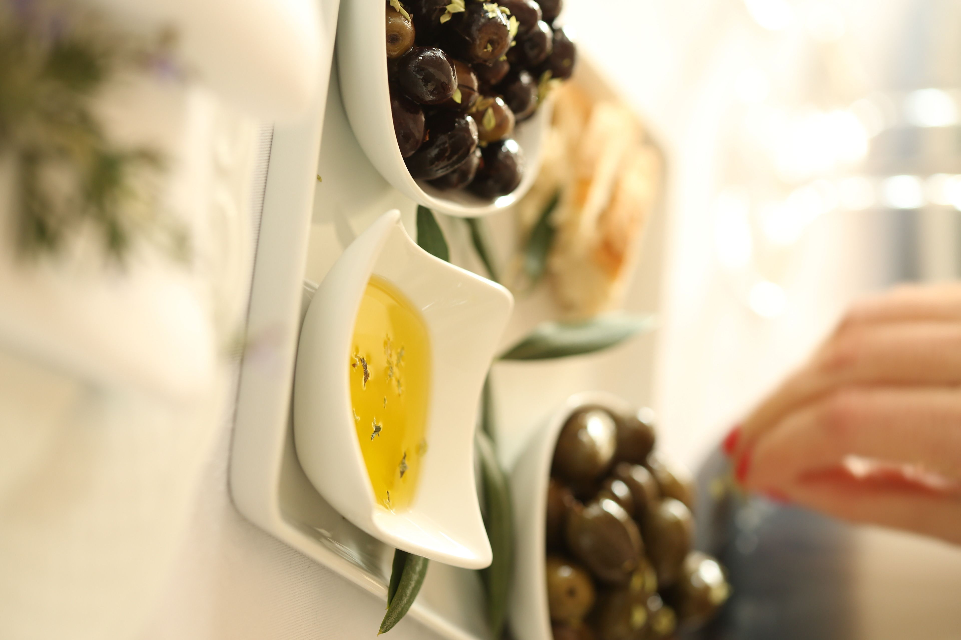 A close-up of a white plate with olives and a small dish of olive oil.
