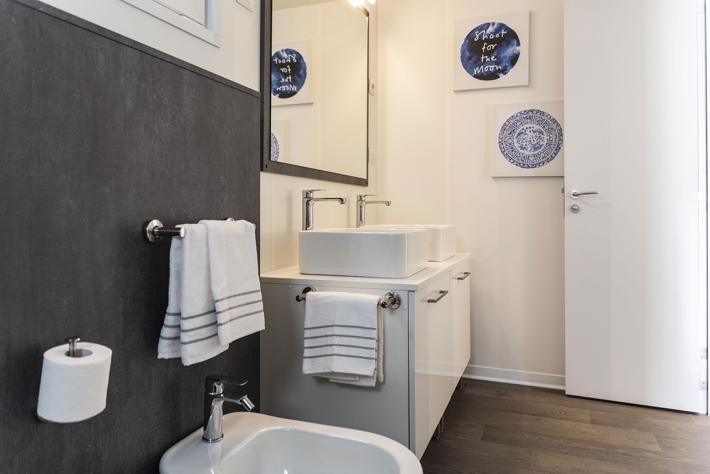 Une salle de bain moderne avec un lavabo blanc, un miroir et deux serviettes accrochées au mur.