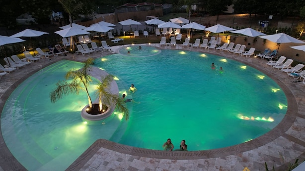 A circular pool with multiple lounge chairs and umbrellas around it. - Flaminio Village Bungalow Park - Campground (Rome)