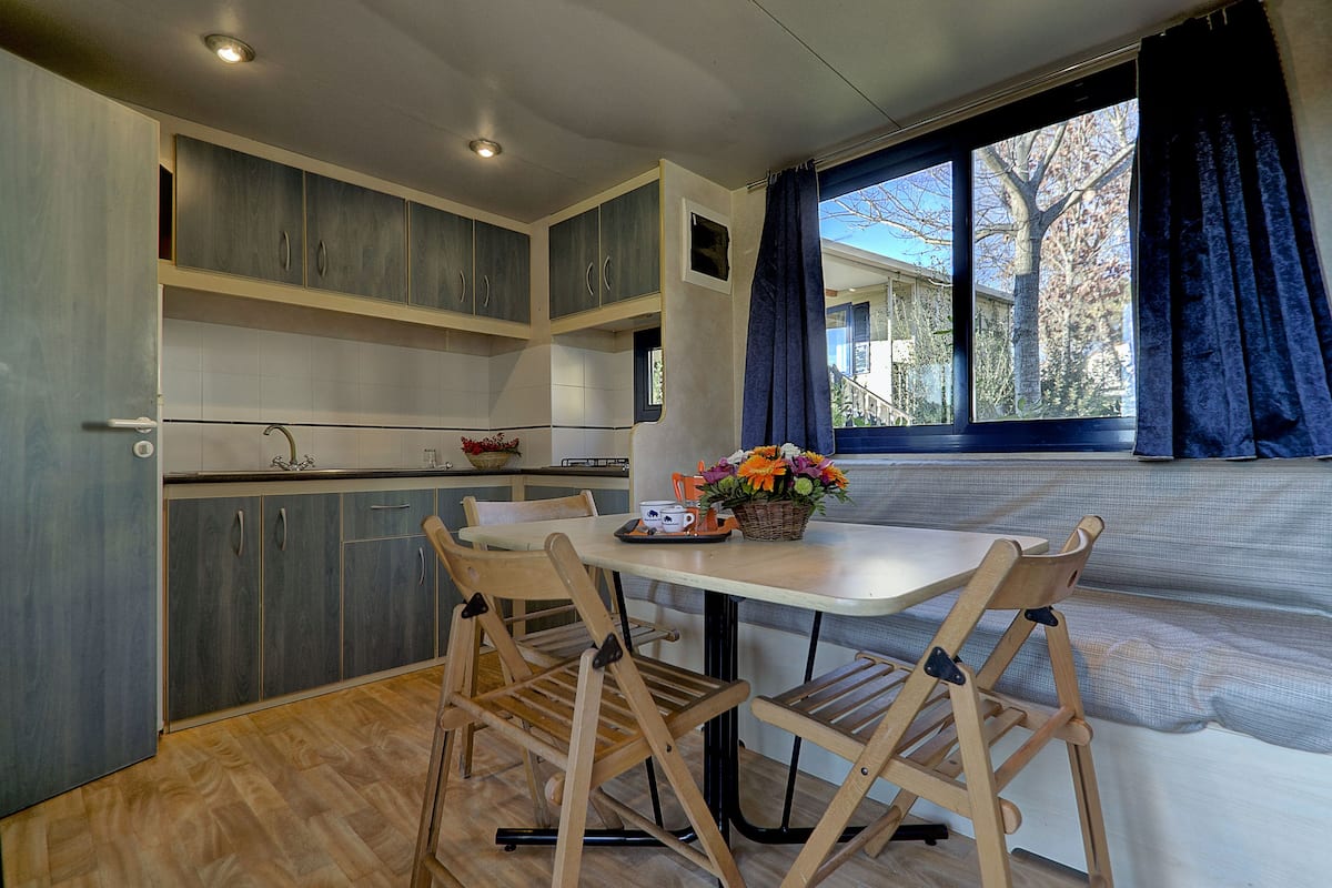 A compact kitchen with wooden cabinets, a dining table, and chairs.