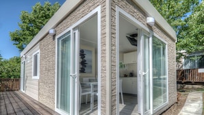 A modern house with a stone facade, large sliding glass doors, and a deck. - Flaminio Village Bungalow Park - Campground (Rome)