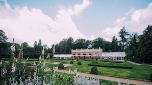 A large building with a glass conservatory, surrounded by well-manicured gardens and trees. - Landgoed Hotel Groot Warnsborn (Arnhem)