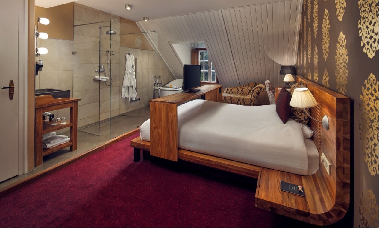 Un dormitorio moderno con una cama de madera, ducha de vidrio y alfombra roja.