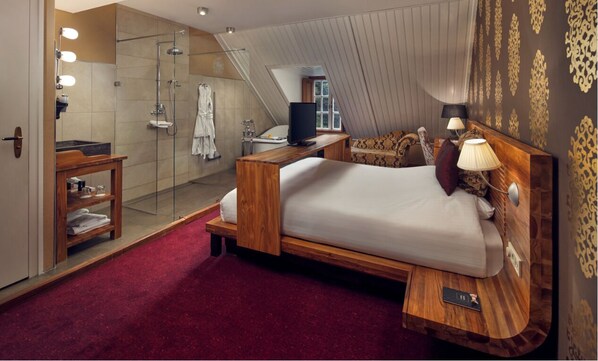 Un dormitorio moderno con una cama de madera, ducha de vidrio y alfombra roja.