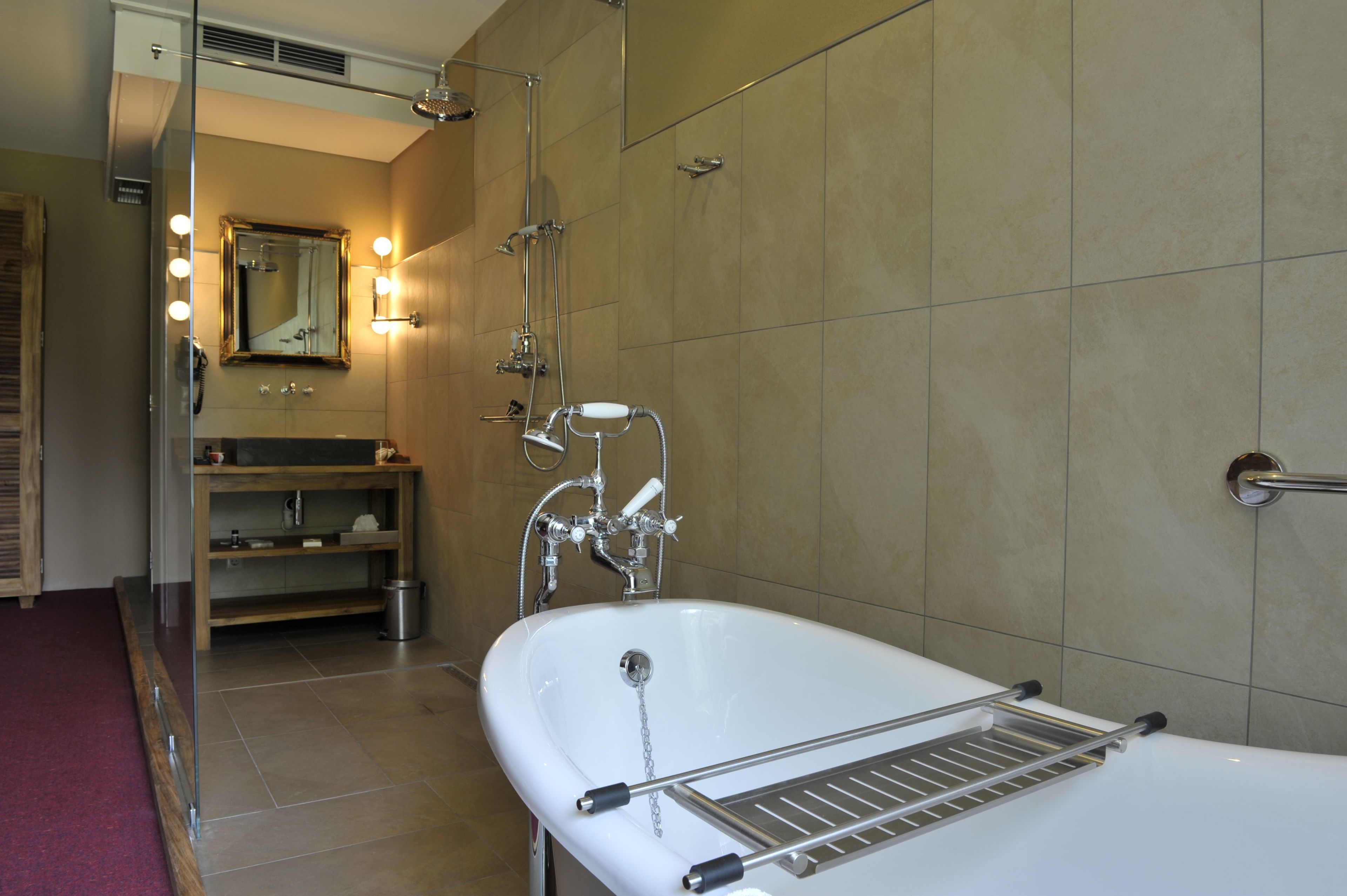 Un baño con una bañera independiente, un tocador con espejo e iluminación, y una zona de ducha.