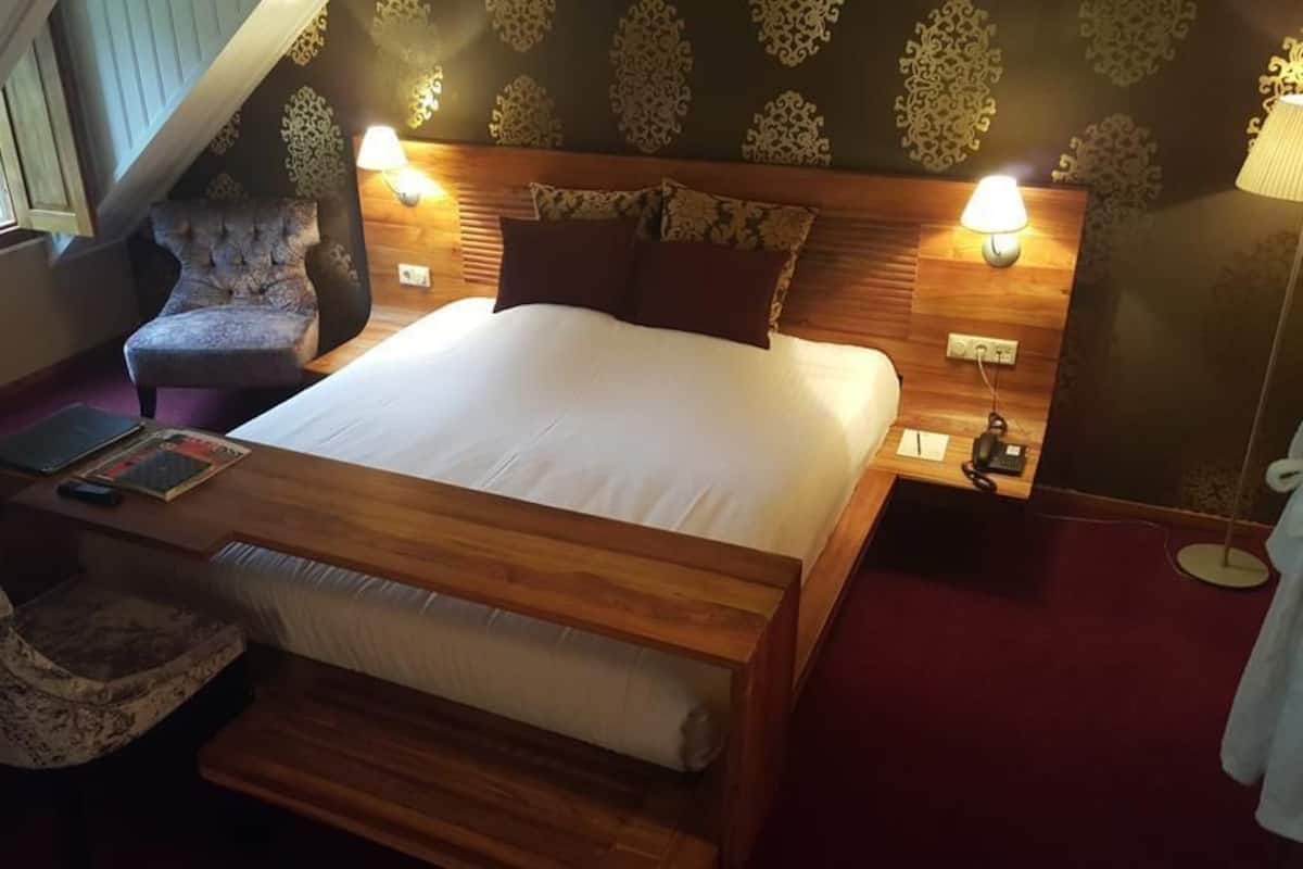 A bedroom with a wooden bed, two bedside tables, a chair, and a lamp.