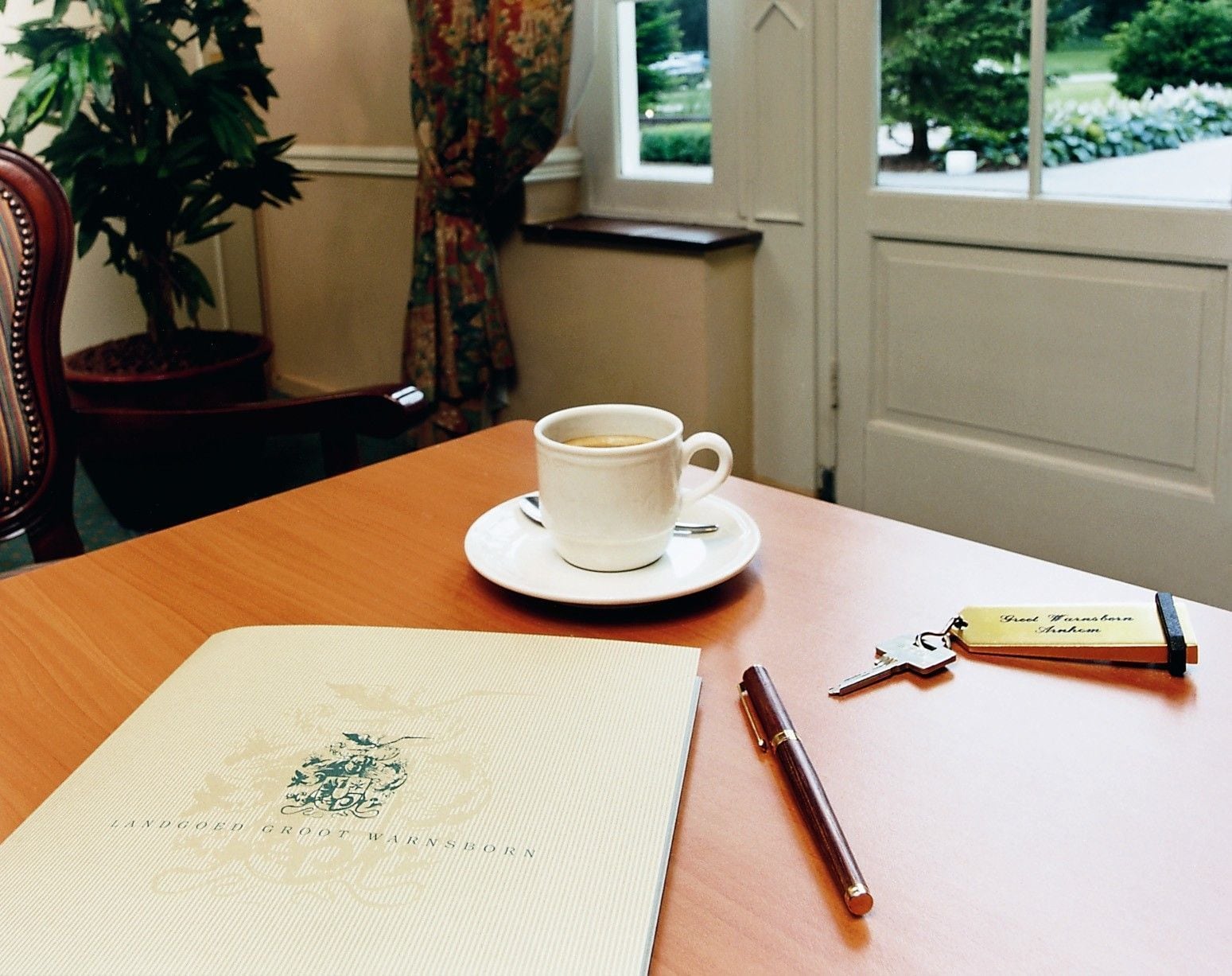 A table with a cup of coffee, a pen, a keychain, and a menu.