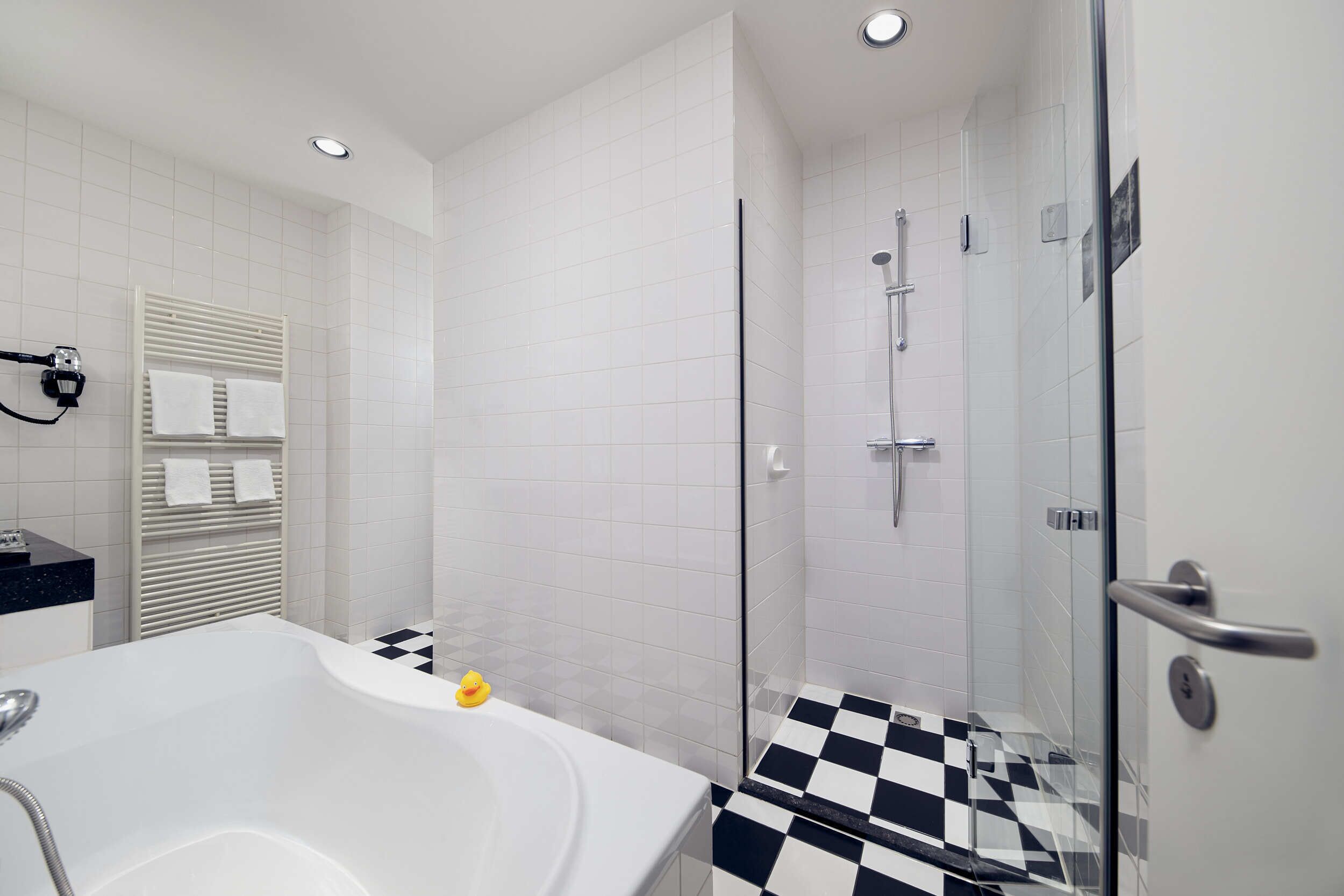 A modern bathroom with a bathtub, a shower, and a checkered floor.