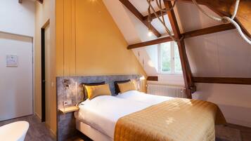 Une chambre avec un grand lit, des poutres en bois, une fenêtre et un radiateur.