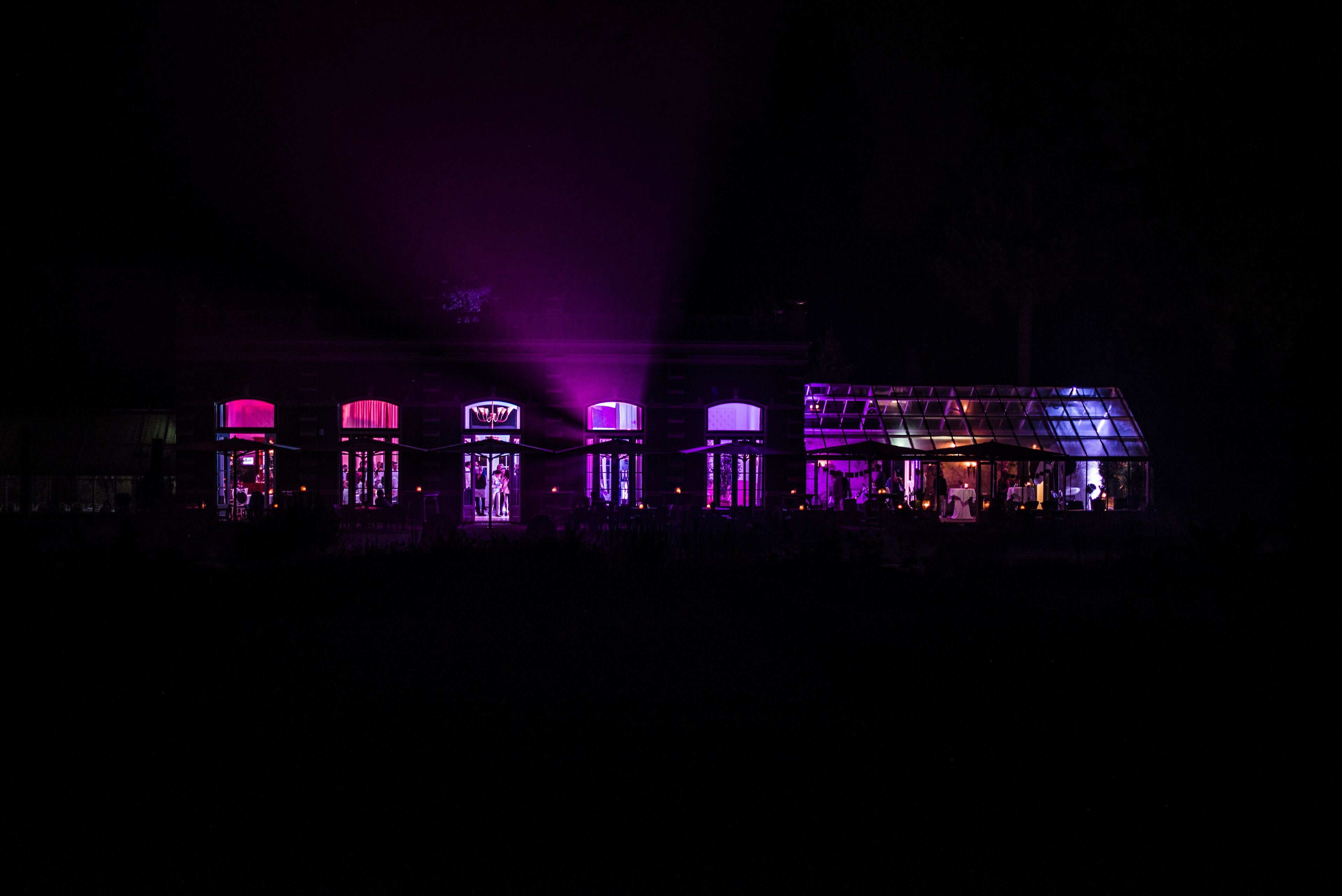 A building with multiple illuminated structures, possibly a hotel or event venue, with a dark surrounding environment.