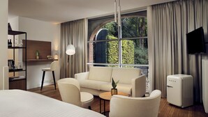 A modern hotel room with a large bed, a sofa, a coffee table, a desk, and a television. - Landgoed Hotel Groot Warnsborn (Arnhem)