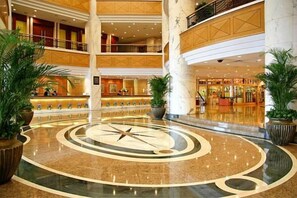 Un vestíbulo de hotel de varios niveles con un diseño circular central, varios pisos y plantas en macetas.