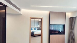 Quarto de hotel moderno com uma cama, uma televisão e um armário de madeira.